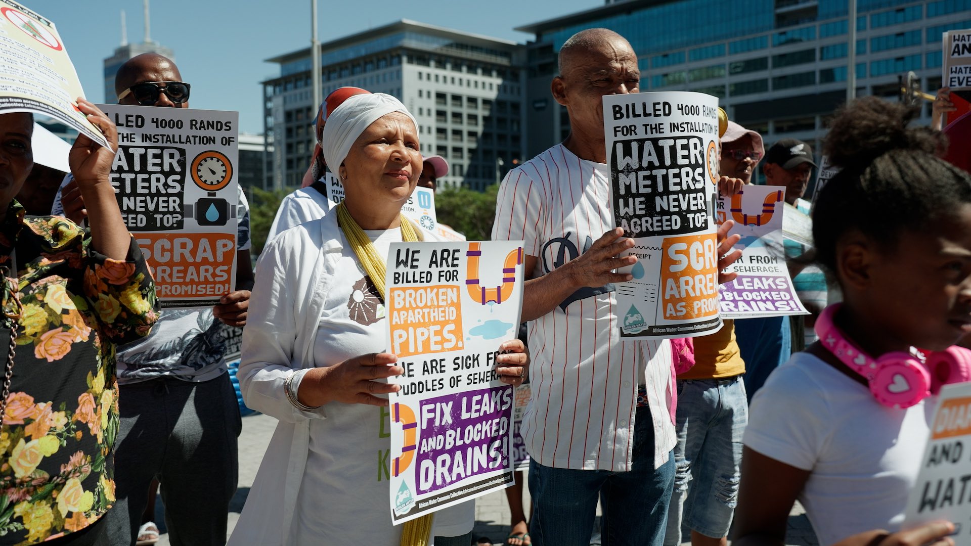 Demonstrators stand outside a building, holding signs that convey their messages during a public protest.