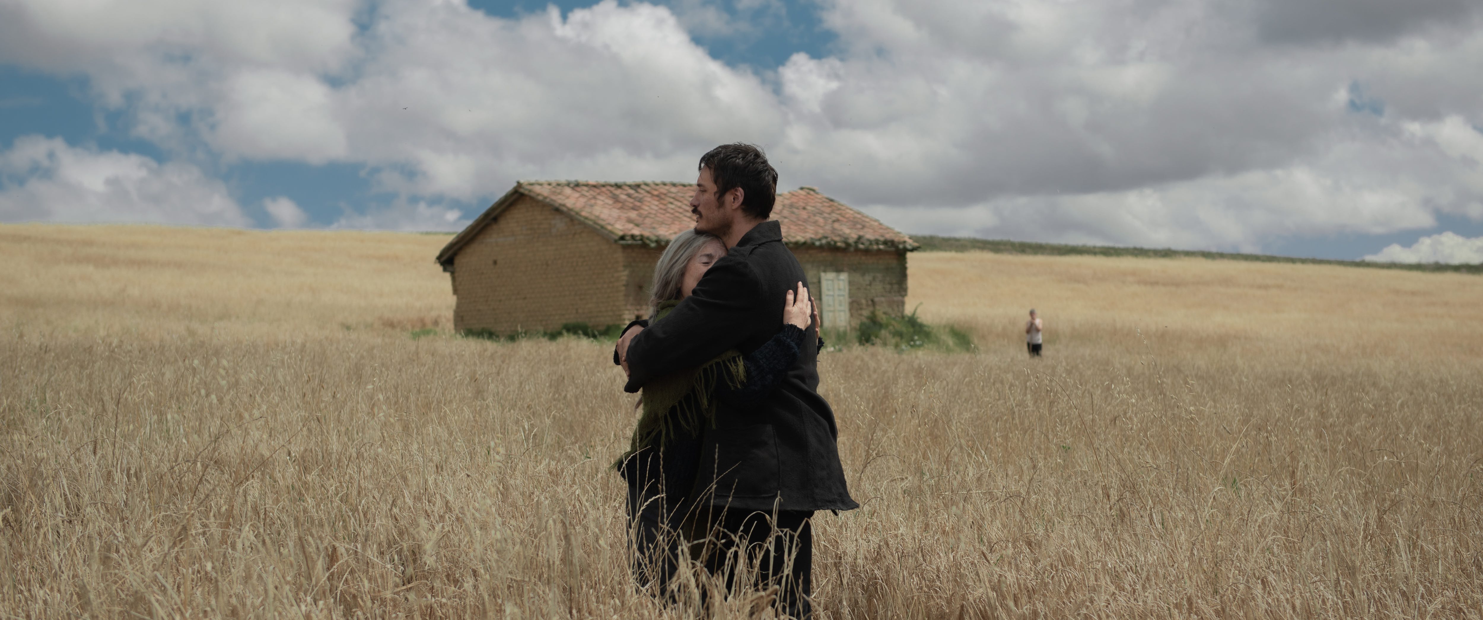 A mother and son embrace in a wheat field