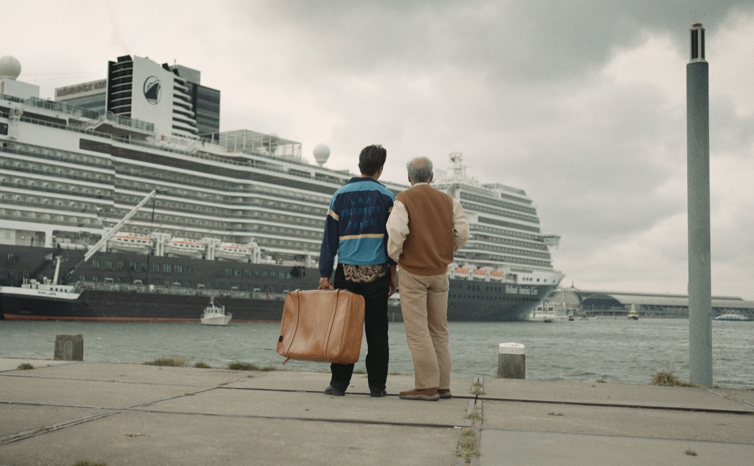 A grandparent and grandchild stand in front of a big ship